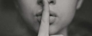 Banner für Blogbeitrag zum Thema Whistleblowing zeigt Person, die Zeigefinger an die Lippen legt