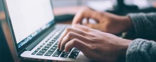 Banner für Blogbeitrag zum Thema Ferialpraktika zeigt eine Arbeitssituation am Laptop