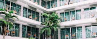 Banner für Blogbeitrag zum Thema Hotellerie zeigt ein Hotel mit Balkons und Palmen