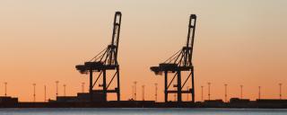 Banner für Blogbeitrag zum Thema Restrukturierungsverfahren zeigt Kräne vor orangem Himmel