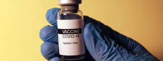 Banner für Blogbeitrag zum Thema COVID-19 Impfung zeigt eine Hand, die Impfstoff hält