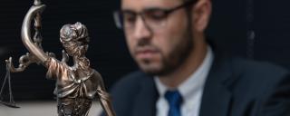 Banner für Blogbeitrag zum Thema Wozu überhaupt Rechtsethik? zeigt Statue der Justitia vor einer Person im Anzug