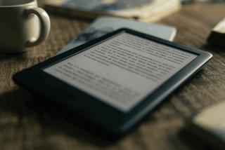 Teserbild zu E-Reader zeigt einen E-Reader auf einem Tisch mit Büchern und Teetasse